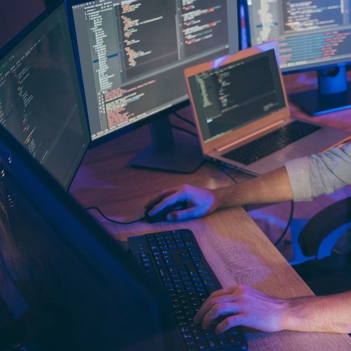 a man using a laptop computer sitting on top of a desk